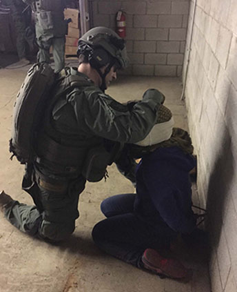 a firefighter in ballistic safety equipment bandages a civilian during a training exercise