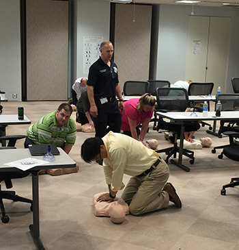 a firefighter/paramedic observes as citizens practice chest compressions on mannequins