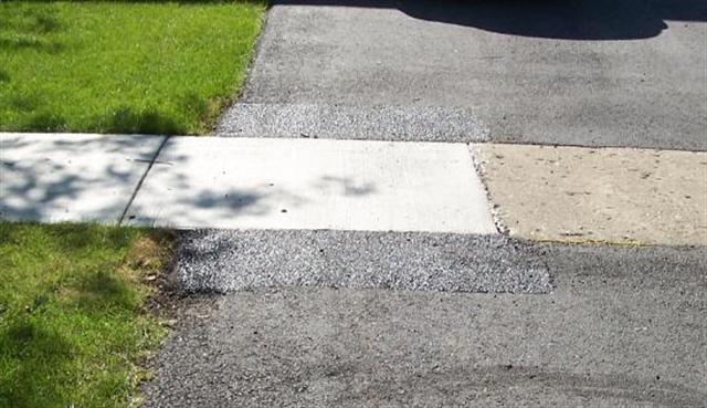 Repaired section of concrete along a driveway, which has also been repaired