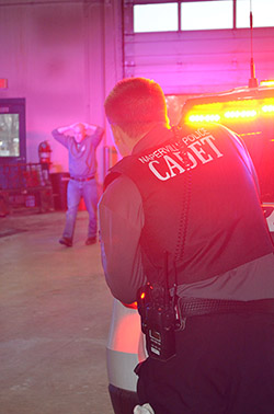 a cadet takes cover behind a squad car during a training