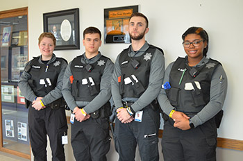 four cadets stand together in uniform in a hallway