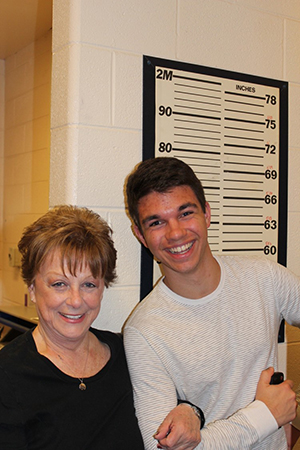A mother and son pose in front of a height chart during a tour of the PD's detention area