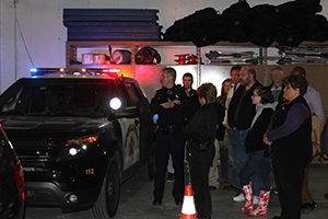 Citizen Police Academy participants gather outside a patrol car with lights on 