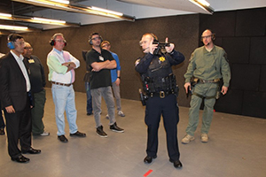A training officer shows Citizen Police Academy participants how to properly handle a firearm
