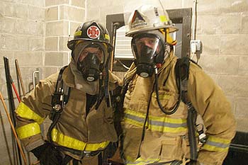 Two citizens stand shoulder to shoulder in firefighter's gear