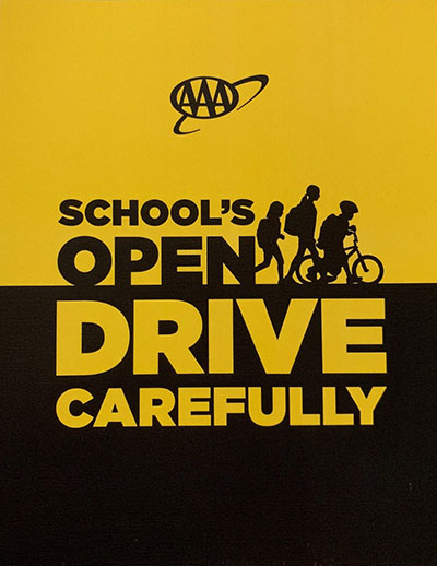 an outline of children wearing backpacks walking and riding a bike with text: School's Open, Drive Carefully